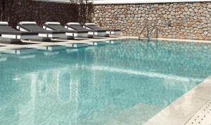 uma piscina com cadeiras e água azul em Sellada Beach em Perissa