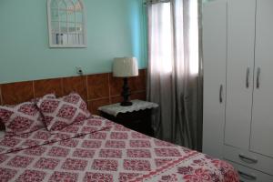 a bedroom with a bed with a red and white quilt at Caribbean Tourist Villa in Port-of-Spain