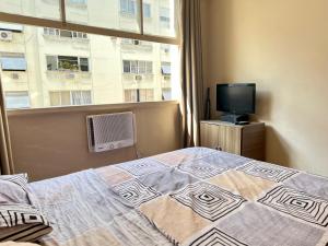 um quarto com uma cama, uma televisão e uma janela em Complete and quiet apartment @ Copacabana no Rio de Janeiro