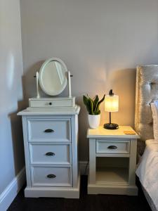 a white dresser with a mirror and a lamp on a table at Large North Facing Room above G Grace & Son in Tring