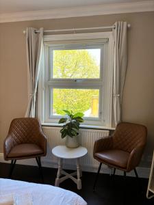 1 dormitorio con 2 sillas y una ventana con una planta en Large North Facing Room above G Grace & Son, en Tring