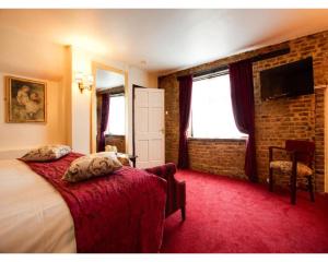 a hotel room with a bed and a brick wall at The Rose And Crown Hotel in Wisbech