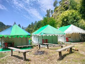 three tents with tables and chairs in a field at Shoolin Cottages & Camp's in Kasol