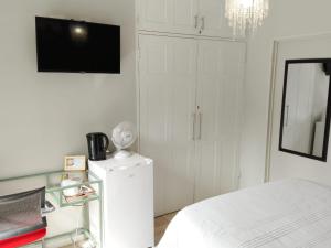 1 dormitorio blanco con 1 cama y TV en South Serene Guest House, en Midrand