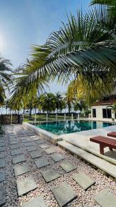 un complejo con piscina con mesa de picnic y palmeras en Anugerah Surf & Dive, en Nembrala