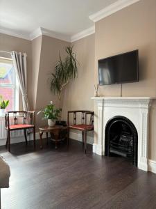 a living room with a fireplace and a tv on the wall at Large West Side Room above G Grace & Son in Tring