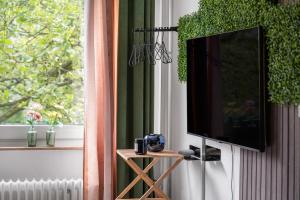 Elle comprend une télévision à écran plat suspendue sur un mur à côté d'une fenêtre. dans l'établissement Urban Jungle Studio Apartment, à Offenbach-sur-le-Main