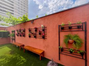 uma parede com bancos e vasos de plantas sobre ela em Bistu Hotel - Vila Nova Conceição em São Paulo