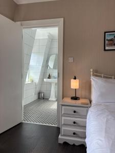 a bedroom with a bed and a bathroom with a sink at Large East Side Room above G Grace & Son in Tring