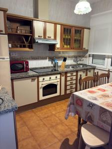 a kitchen with a stove and a table with a tablecloth at CASA DE LA NIÑA,Chalet familiar con gran terraza in Fisterra