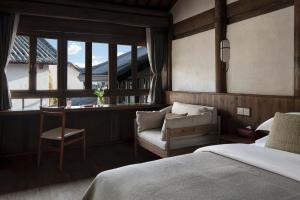 una camera con un letto e una sedia e una finestra di Nandu Bed&Breakfast Lijiang Ancient Town a Lijiang