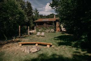 a log bench and two chairs in a yard with a cabin at Dunakavics vendégház stranddal in Zebegény