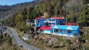 a group of houses on a hill next to a road at JAYANTI MOTHER NATURE HOMESTAY MUNSYARI in Munsyari