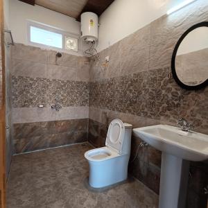 a bathroom with a toilet and a sink and a mirror at JAYANTI MOTHER NATURE HOMESTAY MUNSYARI in Munsyari