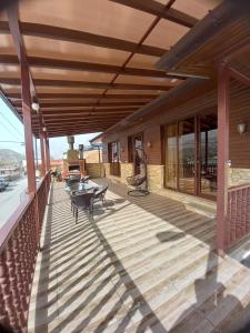 una terraza de madera con mesas y sillas en un edificio en Come & Rest, en Kazbegi