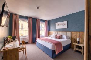una camera con letto con pareti blu e scrivania di The Stroud Hotel a Stroud