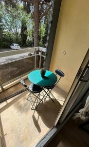 Un balcón con una mesa verde y sillas en un porche en Studio Occitanie-Hopitaux-Facultés, en Montpellier