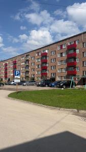 a large brick building with cars parked in a parking lot at Emporium Apartments in Rēzekne
