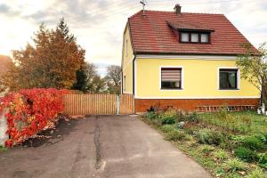 una casa amarilla con techo rojo y entrada en Ferienhaus mit Garten in Thermennähe, en Strebersdorf
