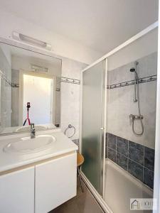 ein weißes Bad mit einem Waschbecken und einer Dusche in der Unterkunft Horizon Sérénité Vue Mer, 4e Étage Confort in Bray-Dunes