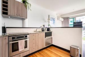 a kitchen with stainless steel appliances and wooden cabinets at Welcome To Your Secluded Luxury Abode in Auckland