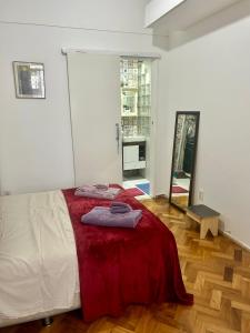 um quarto com uma cama com um cobertor vermelho em Aconchego em botafogo no Rio de Janeiro