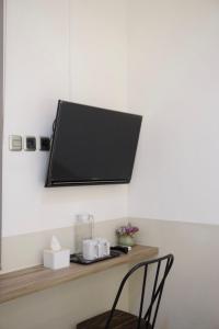 a television on a wall with a chair on a shelf at Aurora House Surabaya in Wijung