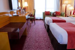 a hotel room with two beds and a desk at Dubai Grand Hotel by Fortune, Dubai Airport in Dubai