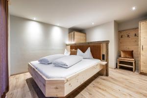 a bedroom with a bed with white sheets and a chair at Mirabelle Pension Sankt Ursula in Saltusio