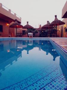 una piscina con agua azul y sombrillas en Riad Desert Man en Merzouga