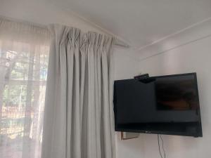 Une télévision à écran plat est installée sur un mur à côté d'une fenêtre. dans l'établissement Sweet Dreams Guest House Schweizer Reneke, à Schweizer-Reineke