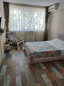 a bedroom with a bed and a chair and a window at Tomis 99 Apart in Constanţa