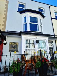 a white house with a table and chairs in front of it at Breeze B&B in Llandudno