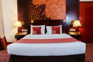a hotel room with a large bed with red pillows at Dubai Grand Hotel by Fortune, Dubai Airport in Dubai