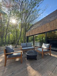 a deck with two chairs and a couch and a table at Tető Mátra Nordic Cabin in Mátraszentimre