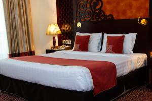 a hotel room with a large bed with red pillows at Dubai Grand Hotel by Fortune, Dubai Airport in Dubai