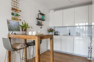 倫敦的住宿－Modern New 1-Bedroom Home Stunning Views，厨房配有木桌和白色橱柜。