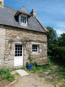 ein altes Steinhaus mit einer weißen Tür und Fenstern in der Unterkunft Petit gîte du Manoir de Keryvoas in Kerlouan