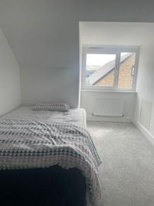 a white bedroom with a bed and a window at Serene Stay Sanctuary in Romford