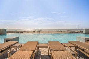 a swimming pool with chairs and a beach at Residence 703 At The Grand in Wildwood