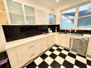 uma cozinha com armários brancos e um piso xadrez preto e branco em Subiaco Heritage House "gem" em Perth