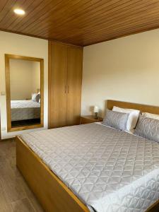 - une chambre avec un grand lit et un miroir dans l'établissement Quinta da Recochina, à Castro Daire