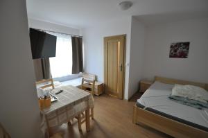 a bedroom with a bed and a table and a television at willa grazyna 2 in Dźwirzyno