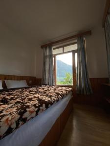 a bedroom with a bed and a large window at Double Dutch, Old Manali in Manāli