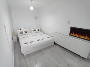 a white room with a bed and a fireplace at Căsuța Piatra Craiului in Zărneşti
