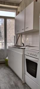 a white kitchen with a stove and a window at Résidence les Sources Mont Dore in Mont-Dore