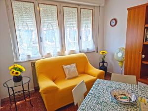 a living room with a yellow couch and a table at A Due Passi Dal Mare in Lido di Camaiore