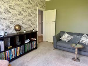 a living room with a couch and a book shelf with books at Lovely, large double bedroom with park view, breakfast in Hazel Grove