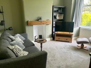 uma sala de estar com um sofá e uma televisão de ecrã plano em Lovely, large double bedroom with park view, breakfast em Hazel Grove