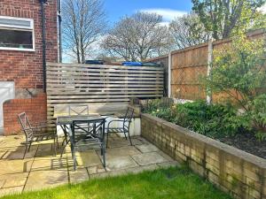 a patio with a table and chairs in a garden at Lovely, large double bedroom with park view, breakfast in Hazel Grove